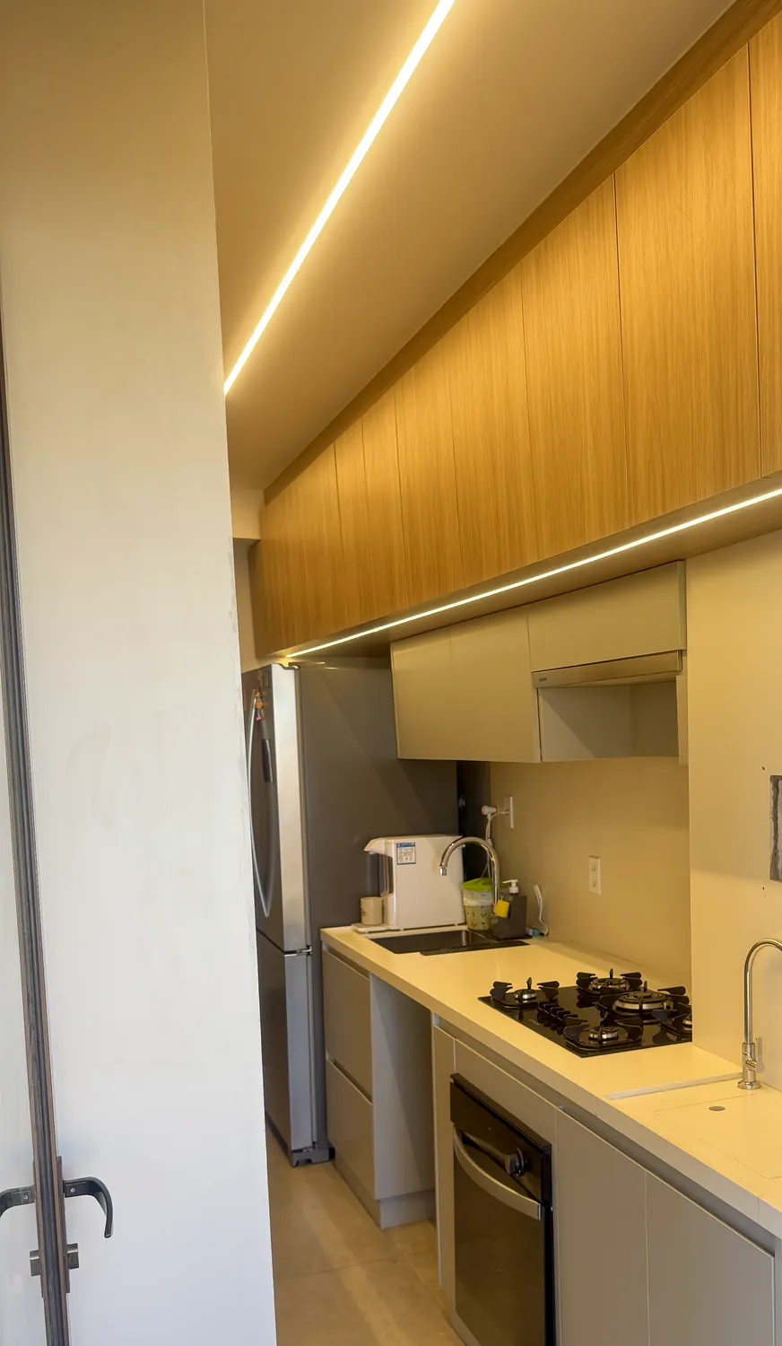 Cozinha planejada em corredor com armários amadeirados e LED embutido, em Águas Claras DF